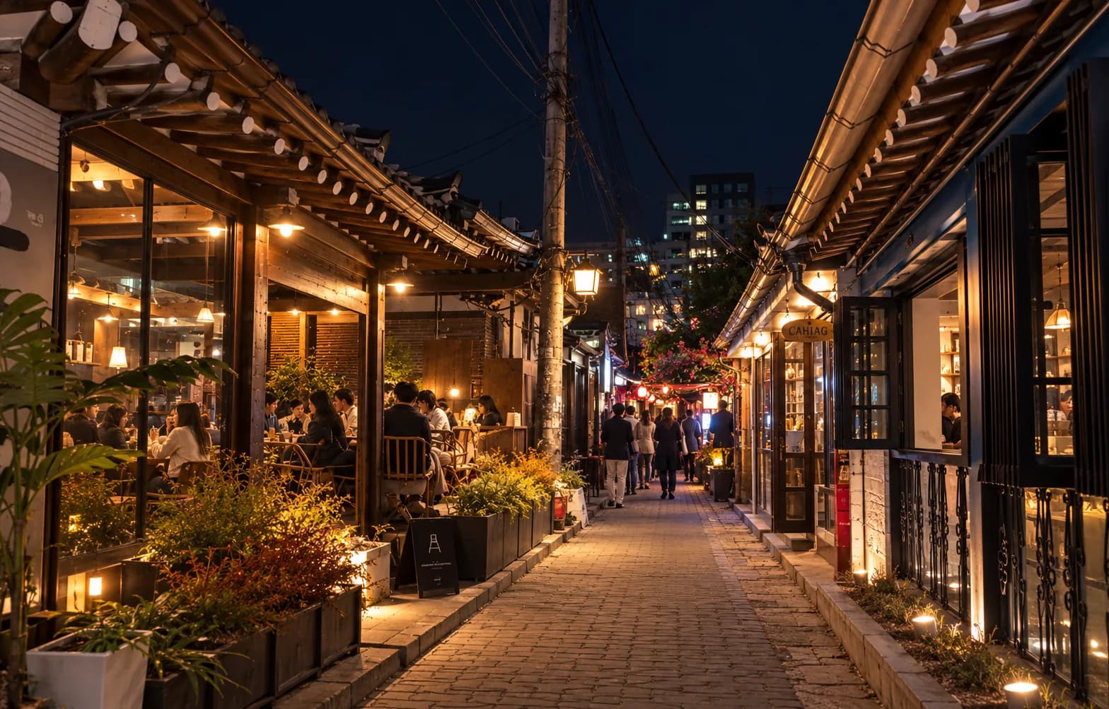 A narrow hanok alley in Ikseon-dong at night, lit by café windows and lanterns